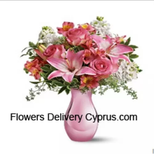 Rosas rosadas, lirios rosados y flores blancas variadas con algunos helechos en un jarrón de vidrio